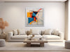 a living room with a white couch and a painting on the wall